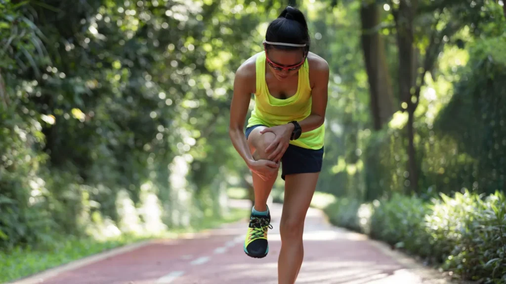 A person holding her knee while jogging