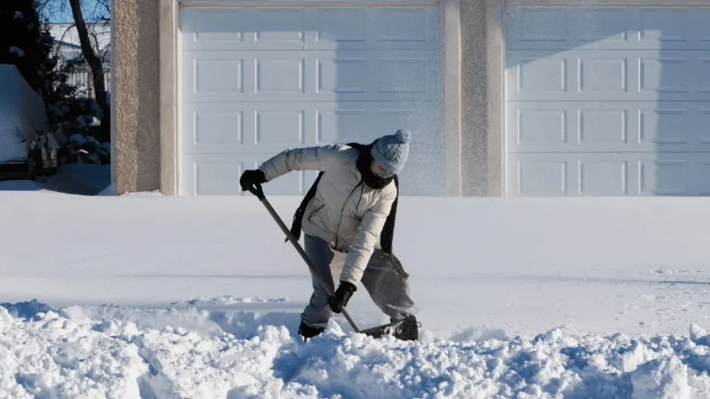 Woman shoveling snow with shovel which is a Winter activities that may impact physical therapy recovery