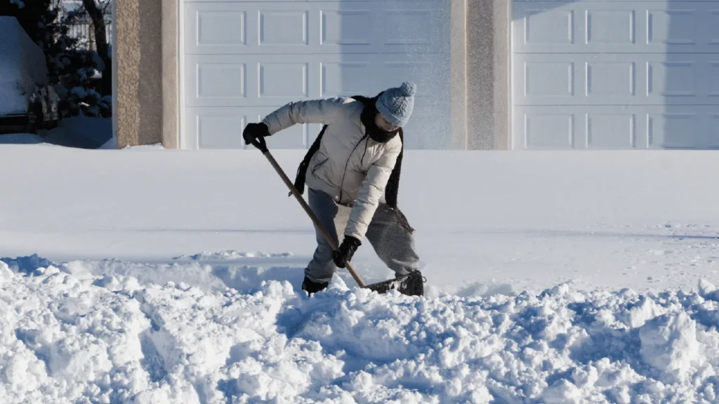 A person shoveling snow in January and trying to prevent getting a winter injury